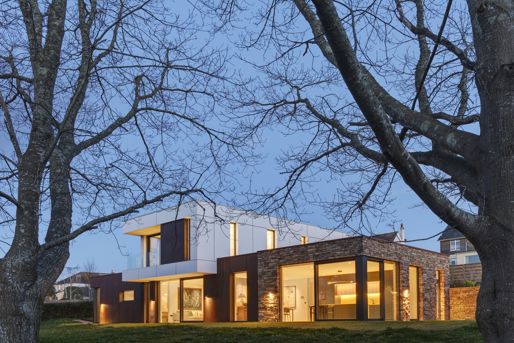 Garden view of the home with illuminated living spaces